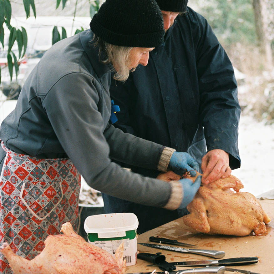 One person shows another where to make the incision to remove the chicken guts